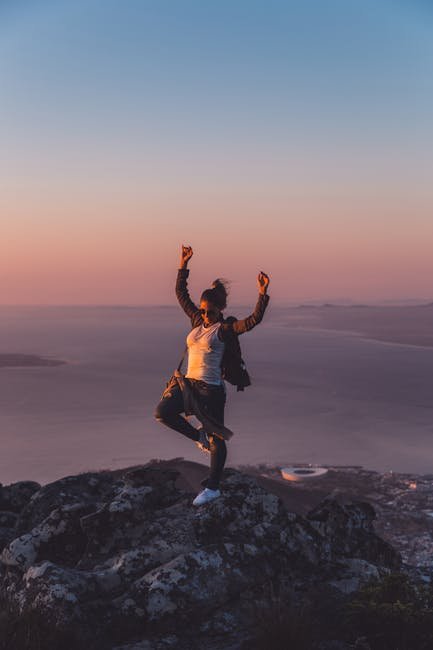 Energetic woman enjoying sunset on a mountain summit overlooking Cape Town, South Africa. Perfect for nature and travel themes.